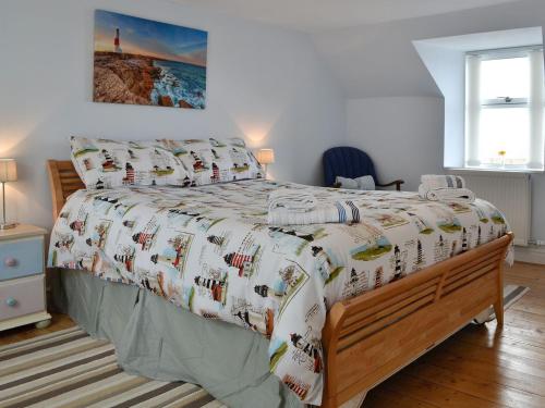 a bedroom with a bed with a comforter on it at Salty Dog in Findochty