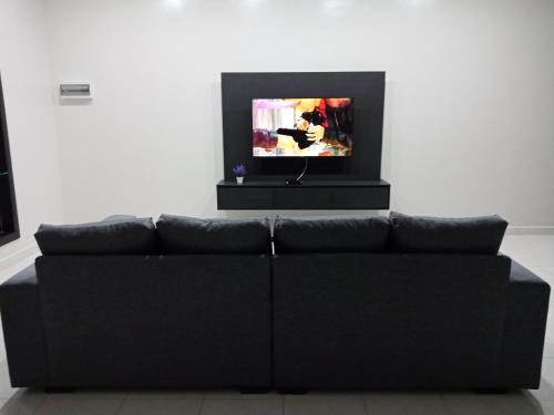 un sofá negro en una sala de estar con TV en 61 Homestay en Sitiawan