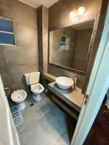 y baño con 2 aseos, lavamanos y espejo. en Departamento Av. España en Mendoza