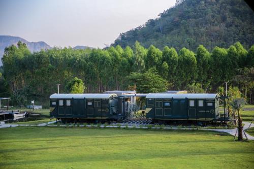 two green train cars parked in a field at Nex Station Kanchanaburi in Kanchanaburi
