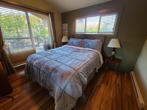 a bedroom with a bed and two windows at A Shack In The Woods in Port Renfrew