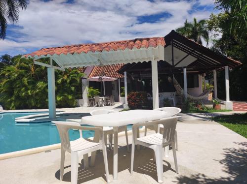 a white table and chairs next to a pool at Casa de Verano Girardot Peñón in Girardot