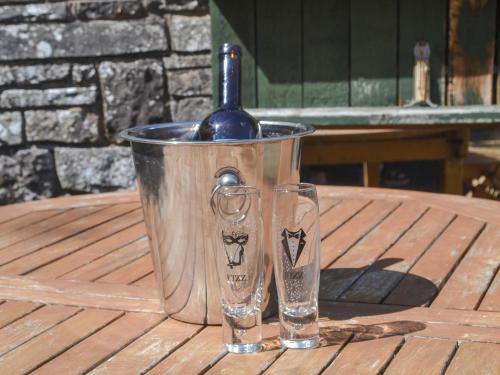 un cubo de metal con una botella y dos vasos sobre una mesa en Ty Sally Jones, en Bwlch