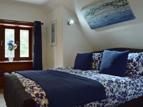 1 dormitorio con cama con sábanas azules y ventana en The Gate House en Markinch