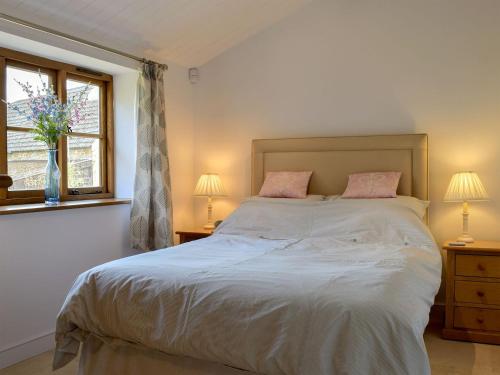 a bedroom with a bed with two lamps and a window at The Old Stables in Swerford