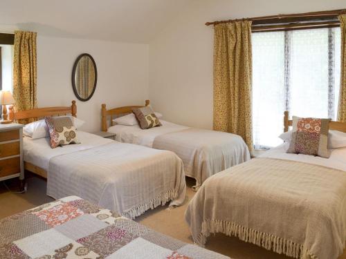 a bedroom with three beds with white sheets at Duvale Barn in Bampton