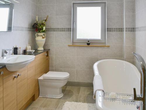 a bathroom with a tub and a toilet and a sink at Kirkland Burn in Amisfield Town