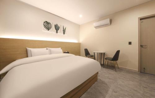 a bedroom with a large white bed and chairs at No25 Hotel Mokpo Sangdong in Mokpo