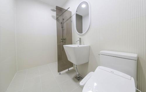 a white bathroom with a toilet and a mirror at No25 Hotel Mokpo Sangdong in Mokpo