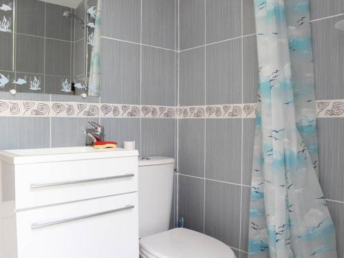 une salle de bain avec toilettes, lavabo et rideau de douche dans l'établissement Maison à Saint-Georges-d'Oléron : 6 couchages, jardin clos, proche centre et plages, tout confort - FR-1-246A-172, à Saint-Georges-dʼOléron