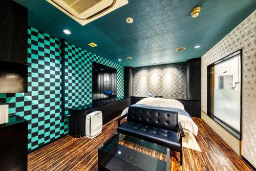 a bedroom with a bed and a couch and a tv at Hotel Lotus Higashiosaka -Adult Only in Osaka