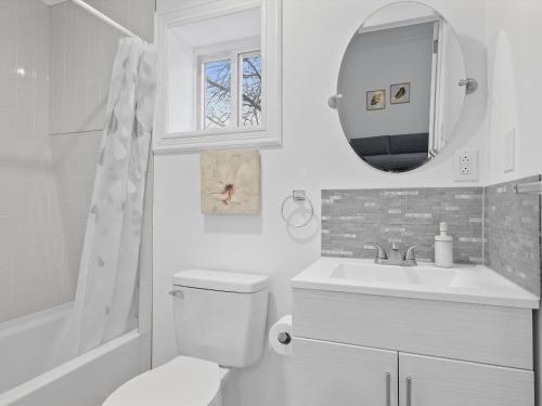 a bathroom with a toilet and a sink and a mirror at Bloomfield/Shadyside @E Stylish and Modern Private Bedroom with Shared Bathroom in Pittsburgh