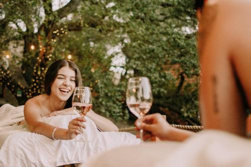 a woman holding two glasses of wine at Boskenvid Hotel - Romantic Treehouses & Skypool in Valle de Guadalupe