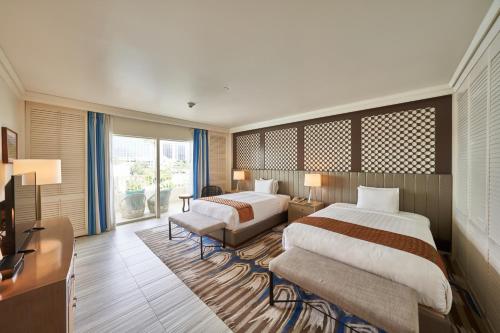 Una habitación de hotel con dos camas y un televisor. en Lotte Hotel Guam, en Tumon