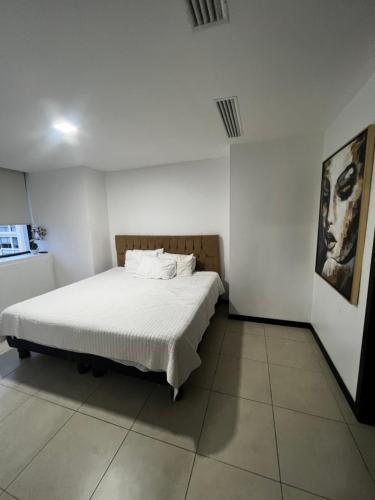 1 dormitorio con 1 cama en una habitación blanca en Cómoda suite en Puerto Santa Ana, en Guayaquil