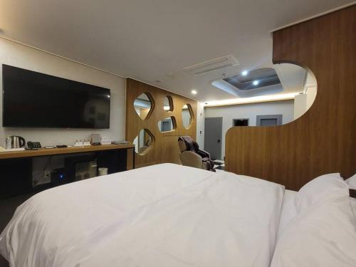 Schlafzimmer mit einem weißen Bett und einem Flachbild-TV in der Unterkunft Bigbell House in Namyangju