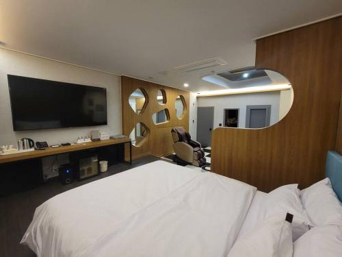 um quarto com uma grande cama branca e uma televisão de ecrã plano em Bigbell House em Namyangju