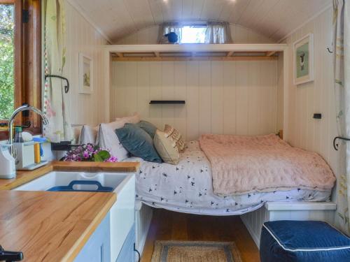 a bedroom with a bed in a tiny house at Herdwick Hut in Twyn Llanan