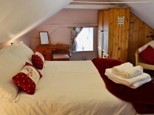 a bedroom with a white bed with towels on it at Little Thatch in Netherbury