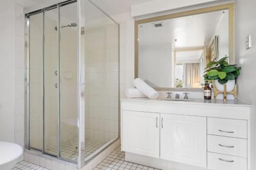 a white bathroom with a shower and a sink at Ocean Breeze at Palm Beach in Gold Coast