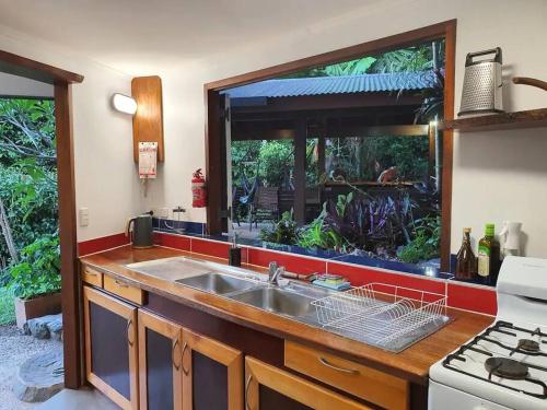 cocina con fregadero y ventana grande en Treeverb Beach House - Daintree en Cow Bay