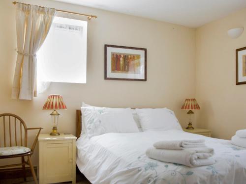 Un dormitorio con una cama blanca con toallas. en The Bothy en Staple