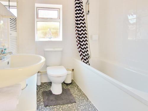 a bathroom with a white tub and a toilet and a sink at Irenic Lodge in Netley