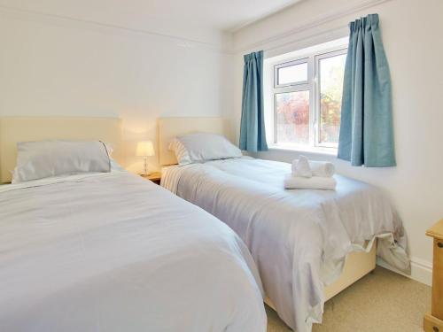 two beds in a bedroom with blue curtains and a window at Irenic Lodge in Netley