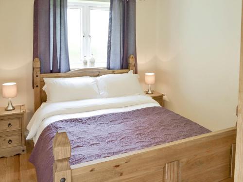 a bedroom with a wooden bed with a window at Lindum Leys in Saint Hilary