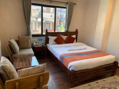 ein Schlafzimmer mit einem Bett, einem Stuhl und einem Fenster in der Unterkunft Hotel Ramanam in Kathmandu