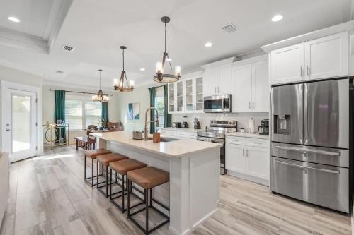 a kitchen with white cabinets and a large island with bar stools at Emerald-Gem-Inn • Laguna Haven/Beach Home! in Panama City Beach