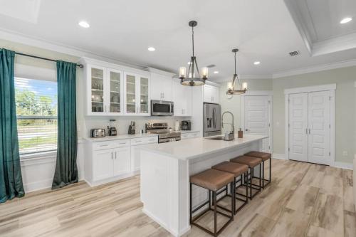 a kitchen with white cabinets and a large island with bar stools at Emerald-Gem-Inn • Laguna Haven/Beach Home! in Panama City Beach