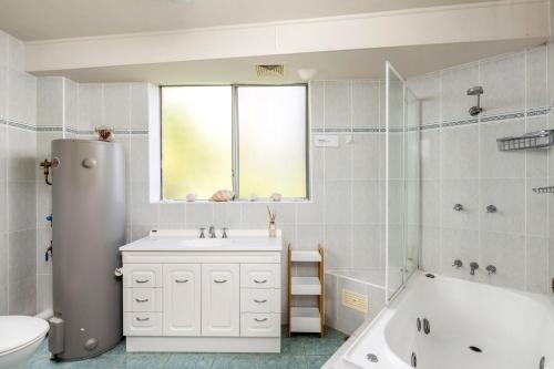 a white bathroom with a tub and a sink and a bath tub at Birdseye View Apartment at Nelson Bay in Nelson Bay