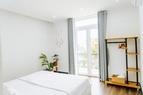 ein weißes Schlafzimmer mit einem Bett und einem großen Fenster in der Unterkunft Modern Greenhouse Garden View Villa in Vung Tau in Vũng Tàu
