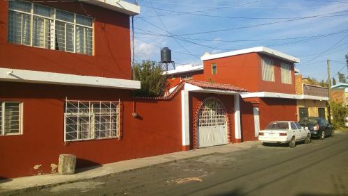 a red building with a white car parked next to a street at DEPARTAMENTOS AMUEBLADOS CELIA in Morelia