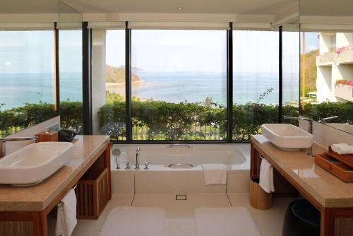 三亞的住宿－三亞半山半島洲際度假酒店，一间带两个盥洗盆和浴缸的浴室以及大窗户。