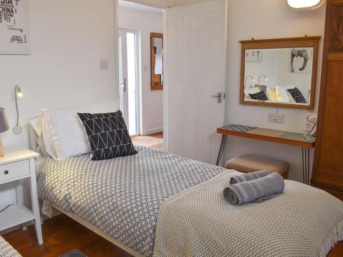um pequeno quarto com uma cama e um espelho em The Wood House em Buckfastleigh