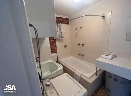 a bathroom with a tub and a toilet and a sink at Ellswood 1 in Jindabyne