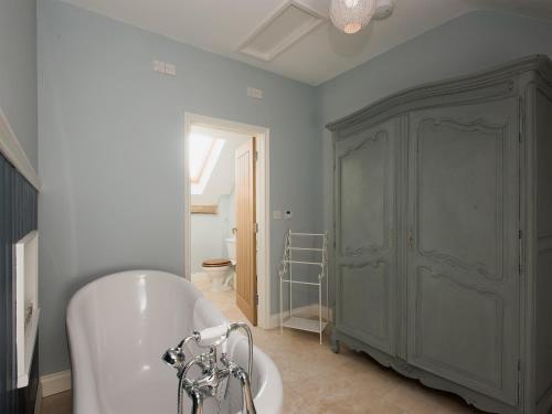 a bathroom with a tub and a gray cabinet at Woodcrest Barn Cottage - Ukc1065 in Shelfanger