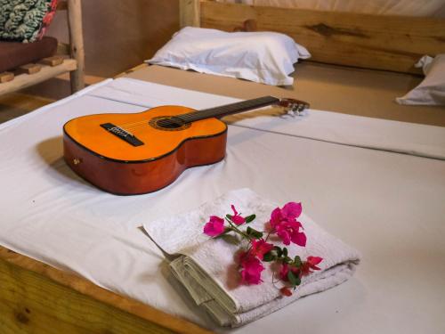 a guitar and a towel with flowers on a bed at blue lilu Kizimkazi in Kizimkazi