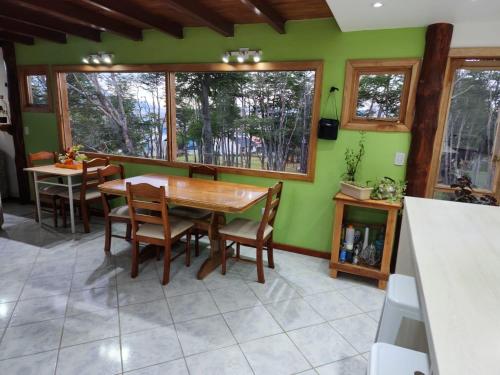 cocina con paredes verdes, mesa de madera y sillas en Habitacion privada en casa de familia en Ushuaia