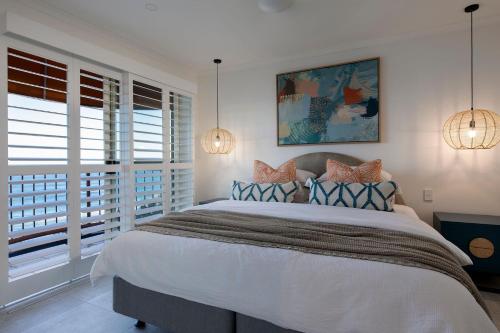 1 dormitorio con 1 cama grande y 2 ventanas en Beachfront Villa, en Coolum Beach