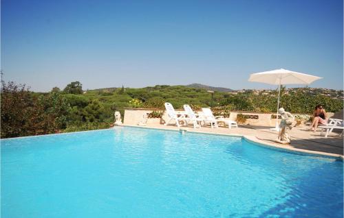 a blue swimming pool with chairs and an umbrella at Nice Home In Sainte Maxime With Wifi in Sainte-Maxime