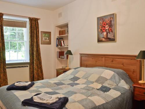 a bedroom with a bed with a quilt on it at Gilminscroft Gatehouse in Sorn