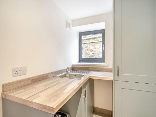 uma pequena cozinha com um lavatório e uma janela em The Granary em Inglewhite