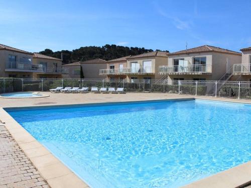 Une grande piscine bleue se trouve en face de certains appartements. dans l'établissement Appart T2 Piscine Clim Parking - Gruissan - FR-1-229-548, à Gruissan