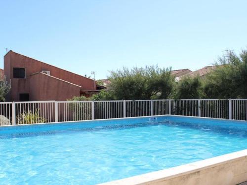 une grande piscine bleue avec une clôture dans l'établissement Charmant pavillon avec mezzanine, piscine et parking, à 300m de la plage du Grazel, Gruissan - FR-1-229-114, à Gruissan