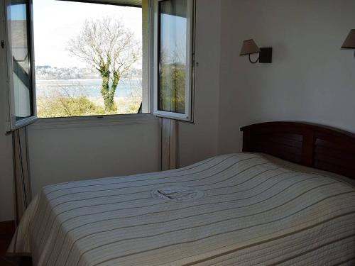 łóżko w sypialni z dużym oknem w obiekcie Maison Louannec, 5 pièces, 8 personnes - FR-1-368-65 w mieście Louannec