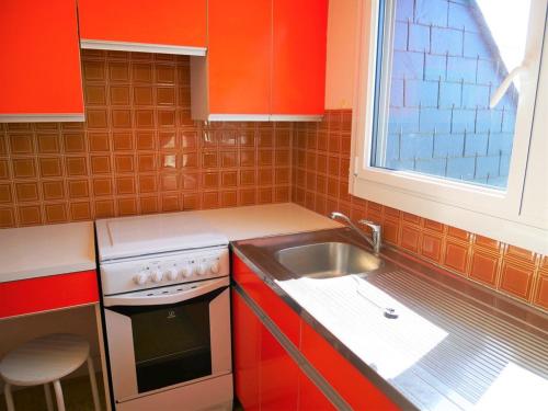 una pequeña cocina con armarios rojos y fregadero en Appartement Quiberon, 2 pièces, 5 personnes - FR-1-478-125, en Quiberon