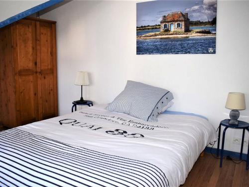 un lit dans une chambre avec un tableau sur le mur dans l'établissement Maison de pêcheur à 50m du port et 300m de la plage avec WIFI, terrasse, et cheminée - Perros-Guirec - FR-1-368-157, à Perros-Guirec